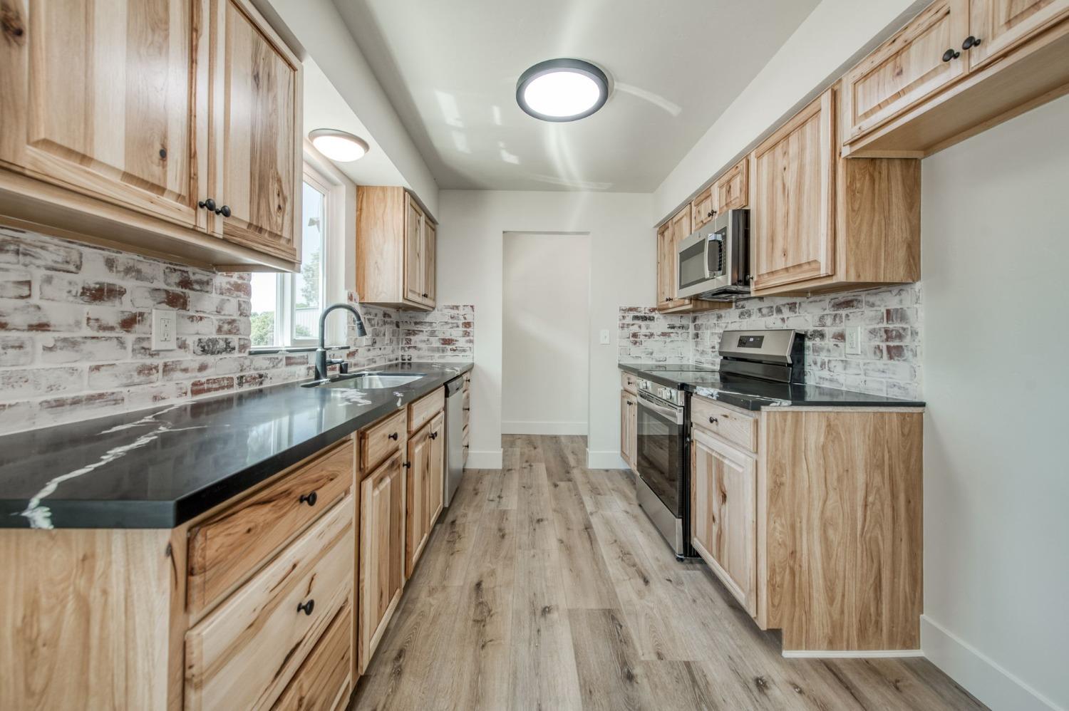 16715 Monreal Road Madera, CA 93636 - Photo 16 of 39 a kitchen with stainless steel appliances granite countertop a stove a sink dishwasher and a refrigerator