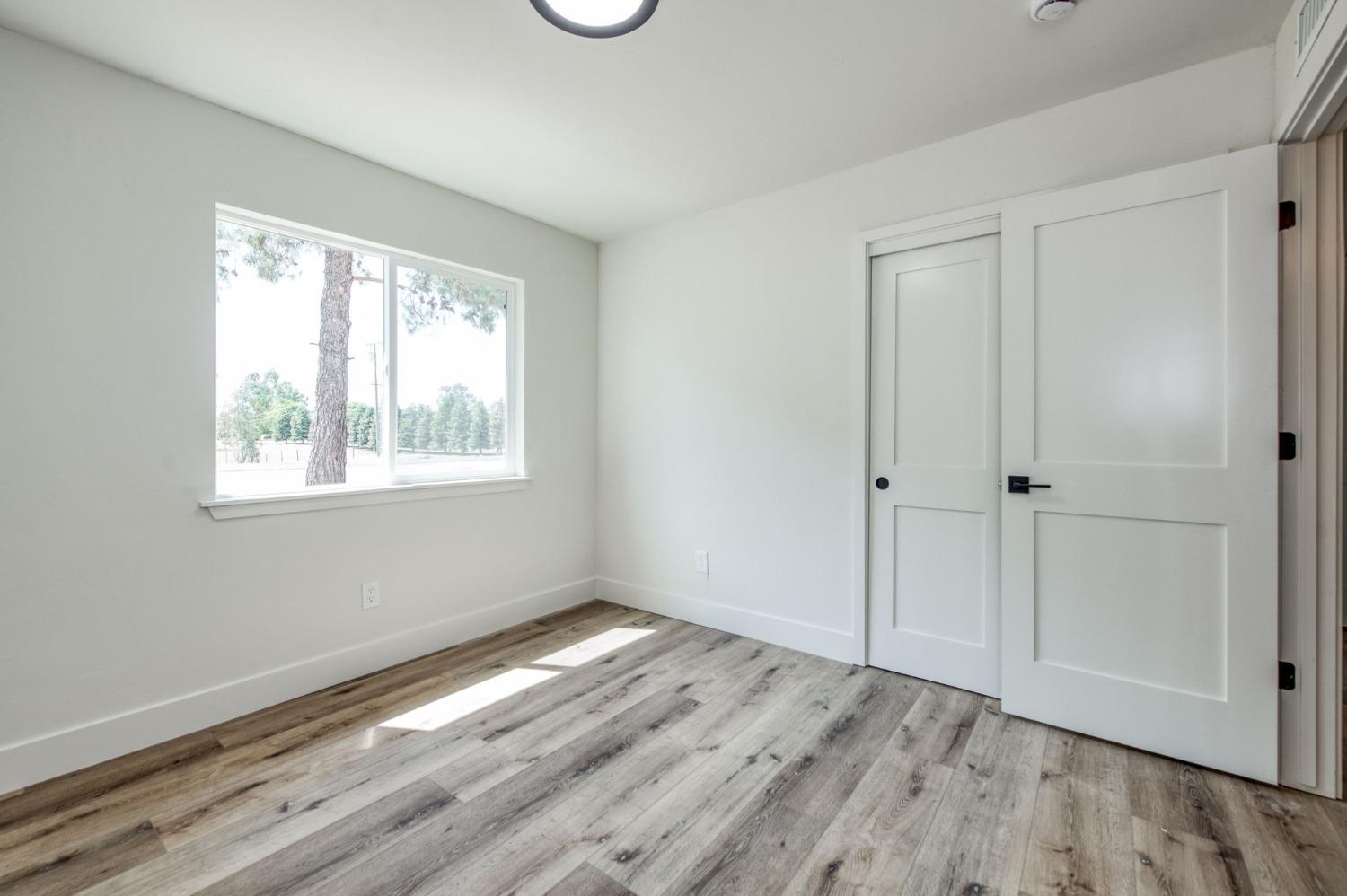 16715 Monreal Road Madera, CA 93636 - Photo 7 of 39 a view of an empty room with wooden floor and a window