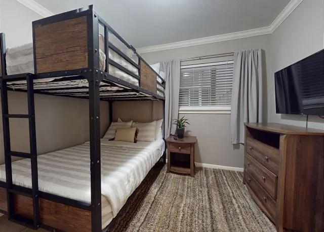 a bedroom with a bed and a flat tv screen on dresser
