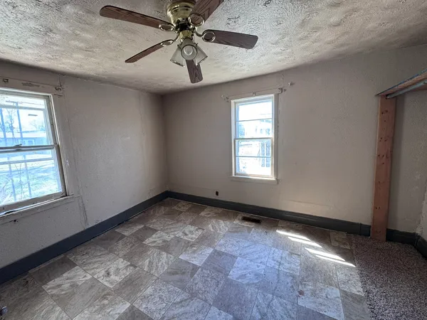 an empty room with windows and fan
