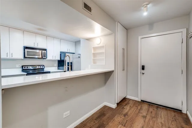 a kitchen with stainless steel appliances a microwave a sink and cabinets