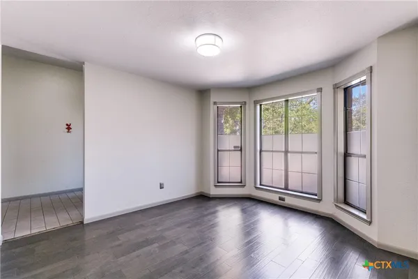 an empty room with windows and ceiling fan