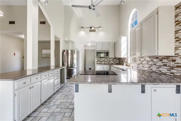 a large kitchen with stainless steel appliances kitchen island granite countertop a sink and cabinets