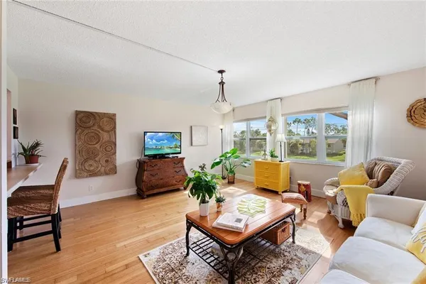 a living room with furniture a large window and potted plants