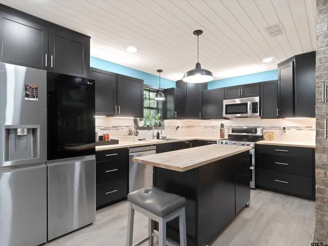 a kitchen with stainless steel appliances kitchen island granite countertop a sink stove and refrigerator