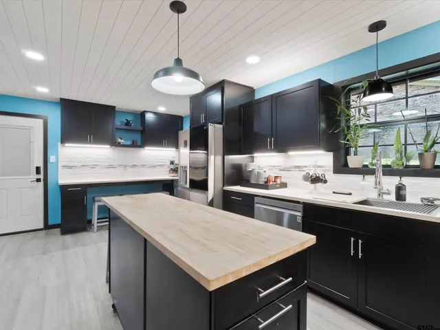 a kitchen with kitchen island a sink counter top space stainless steel appliances and a chandelier