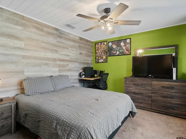 a bedroom with a bed a mirror on the wall and a flat screen tv