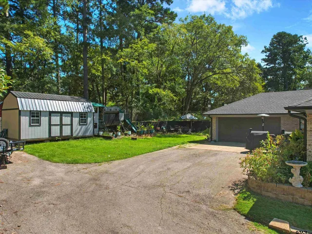 a view of a house with a yard and a large tree