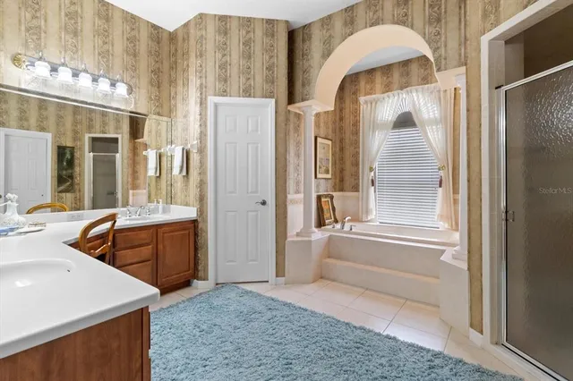 a spacious bathroom with a tub sink and mirror