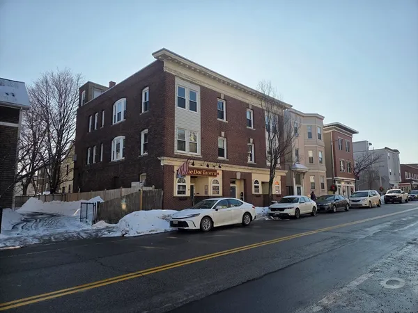 a city street lined with parked cars and buildings
