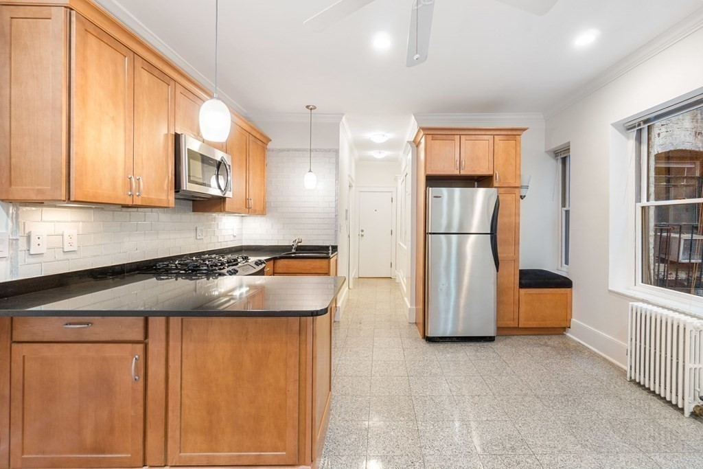 a kitchen with stainless steel appliances granite countertop a refrigerator a stove and a sink with wooden floor