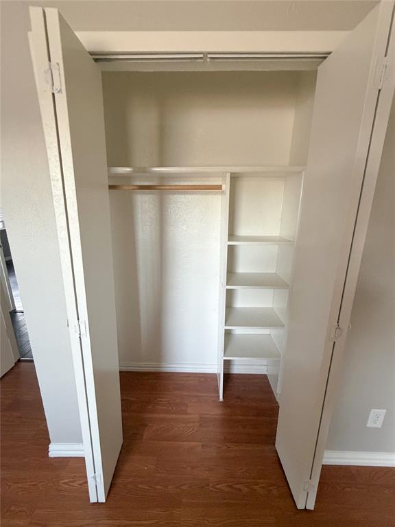 8601 Woodside Road Rowlett, TX 75088 - Photo 17 of 22 Built-in closet with wood-finish flooring, bi-fold doors, integrated shelving, and a hanging rod