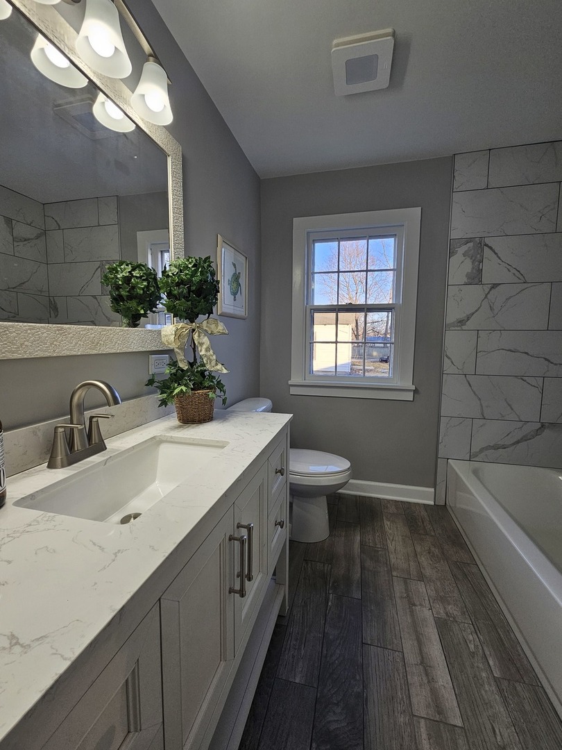 220 South Walnut Street Sycamore, IL 60178 - Photo 9 of 13 a bathroom with a granite countertop sink a toilet a tub and mirror