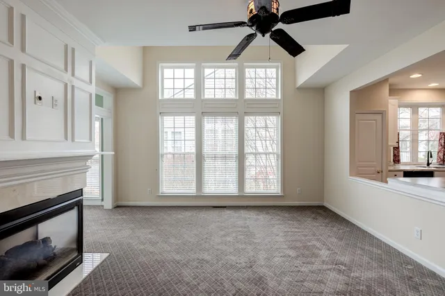 a view of an empty room with kitchen and a window