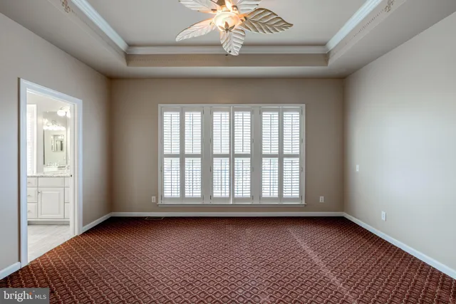 a view of an empty room with chandelier fan and a window