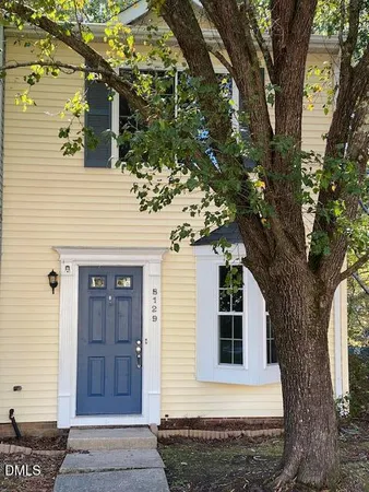 a front view of a house with a tree