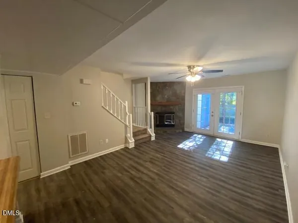 a view of an empty room with window and wooden floor