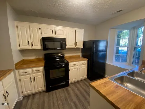 a kitchen with stainless steel appliances granite countertop a refrigerator stove and white cabinets with wooden floor