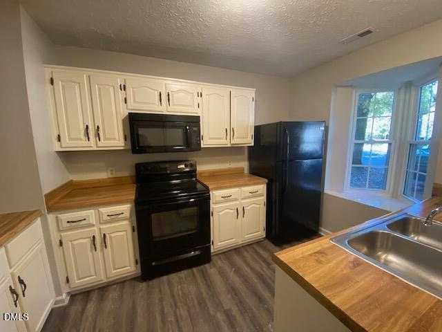 8129 McGuire Drive Raleigh, NC 27616 - Photo 7 of 14 a kitchen with stainless steel appliances granite countertop a refrigerator stove and white cabinets with wooden floor