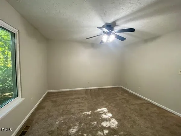 an empty room with a window and a fan
