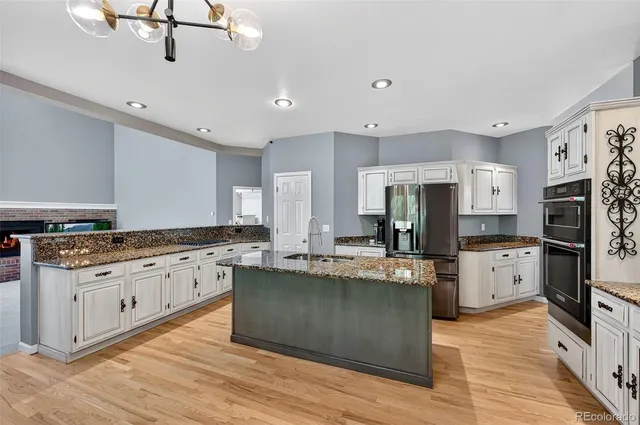 a large kitchen with stainless steel appliances kitchen island granite countertop a stove and a sink