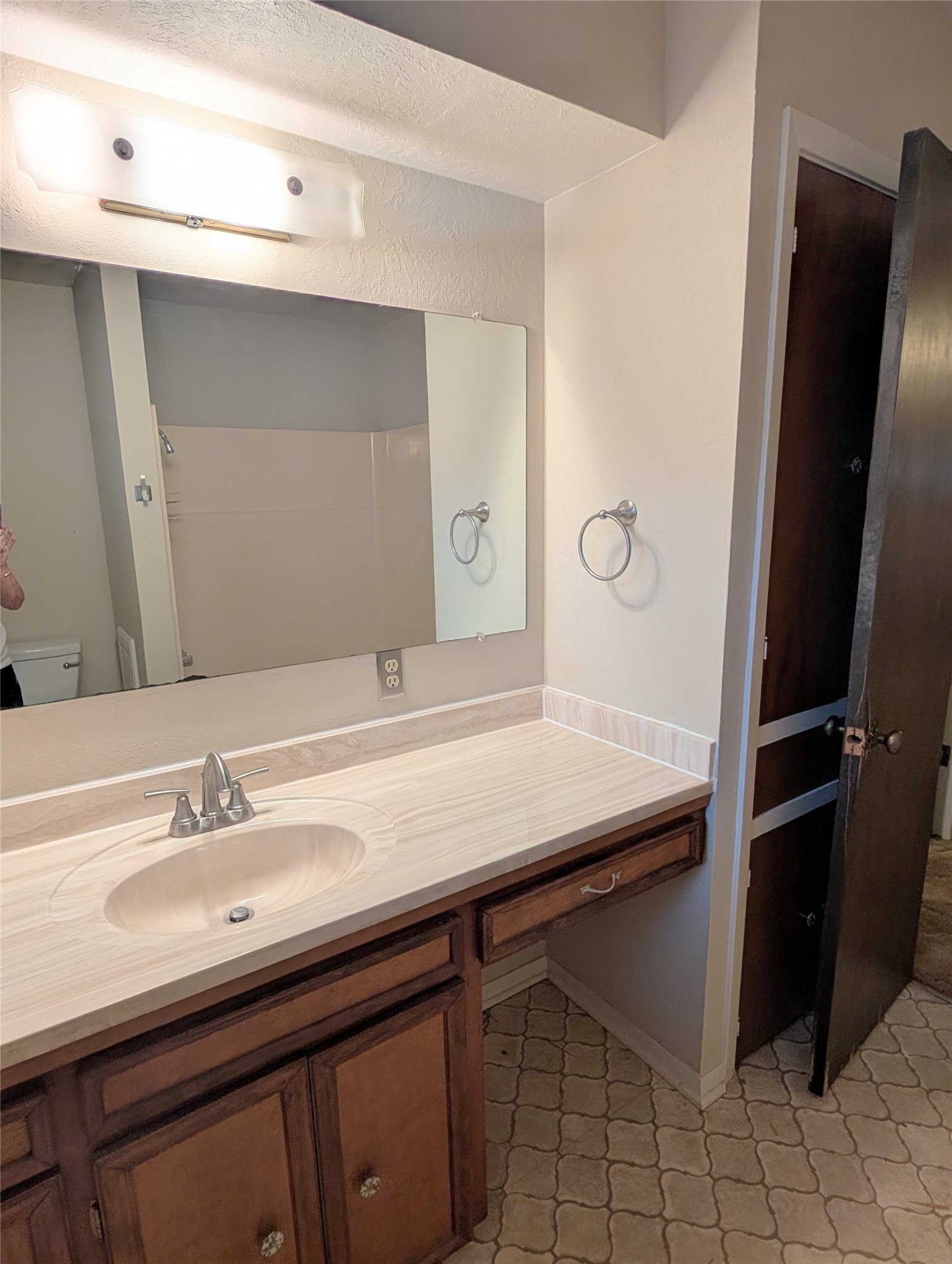 4779 Mixville Road Sealy, TX 77474 - Photo 22 of 47 Guest bathroom features a wooden vanity with a built-in granite sink, a large mirror, and wall-mounted lighting. The space includes a towel ring, neutral tile flooring, and a partially visible shower area.