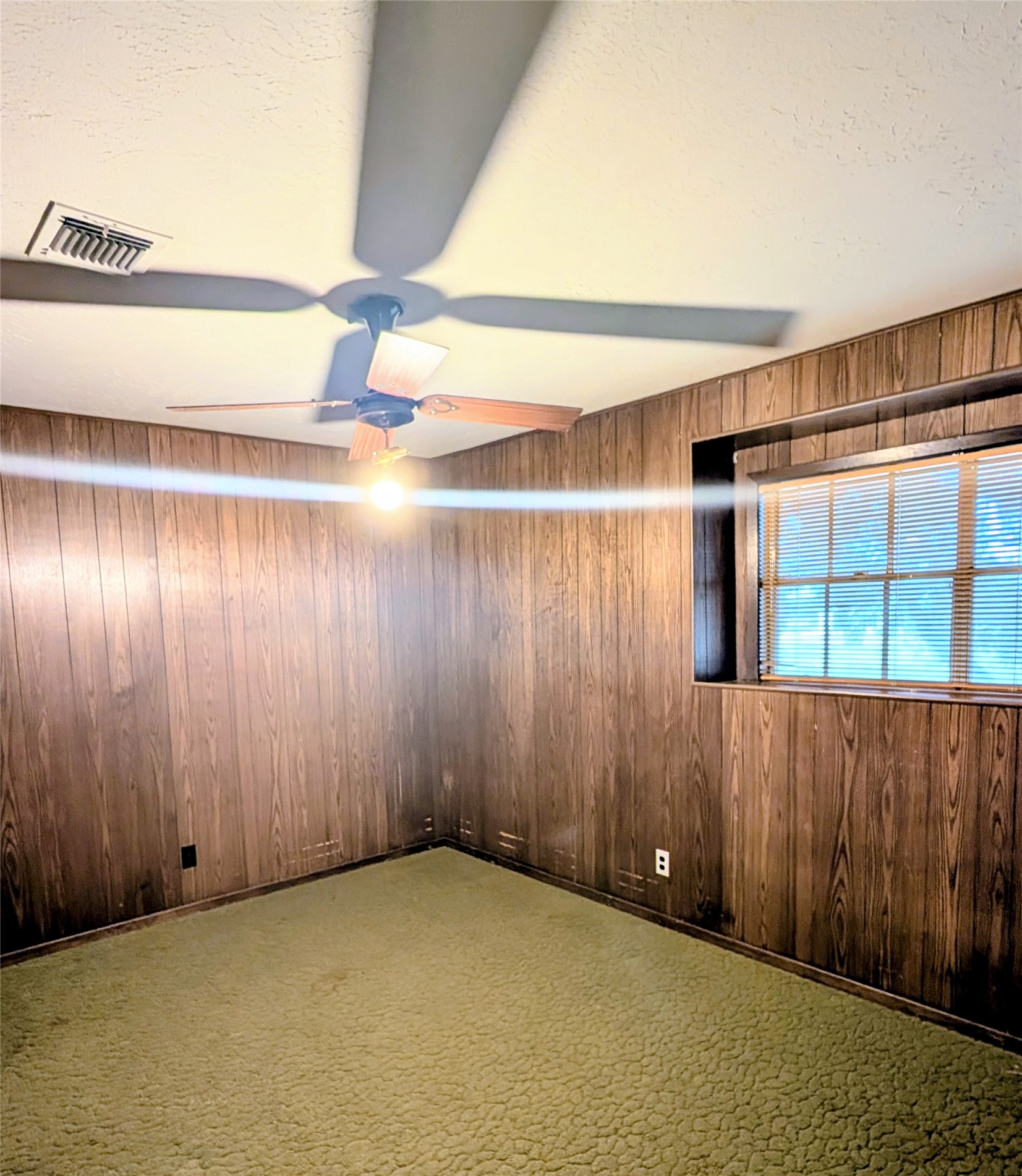 4779 Mixville Road Sealy, TX 77474 - Photo 25 of 47 Bedroom featuring wood-paneled walls, carpet, a ceiling fan, and a window with blinds that provide natural light.