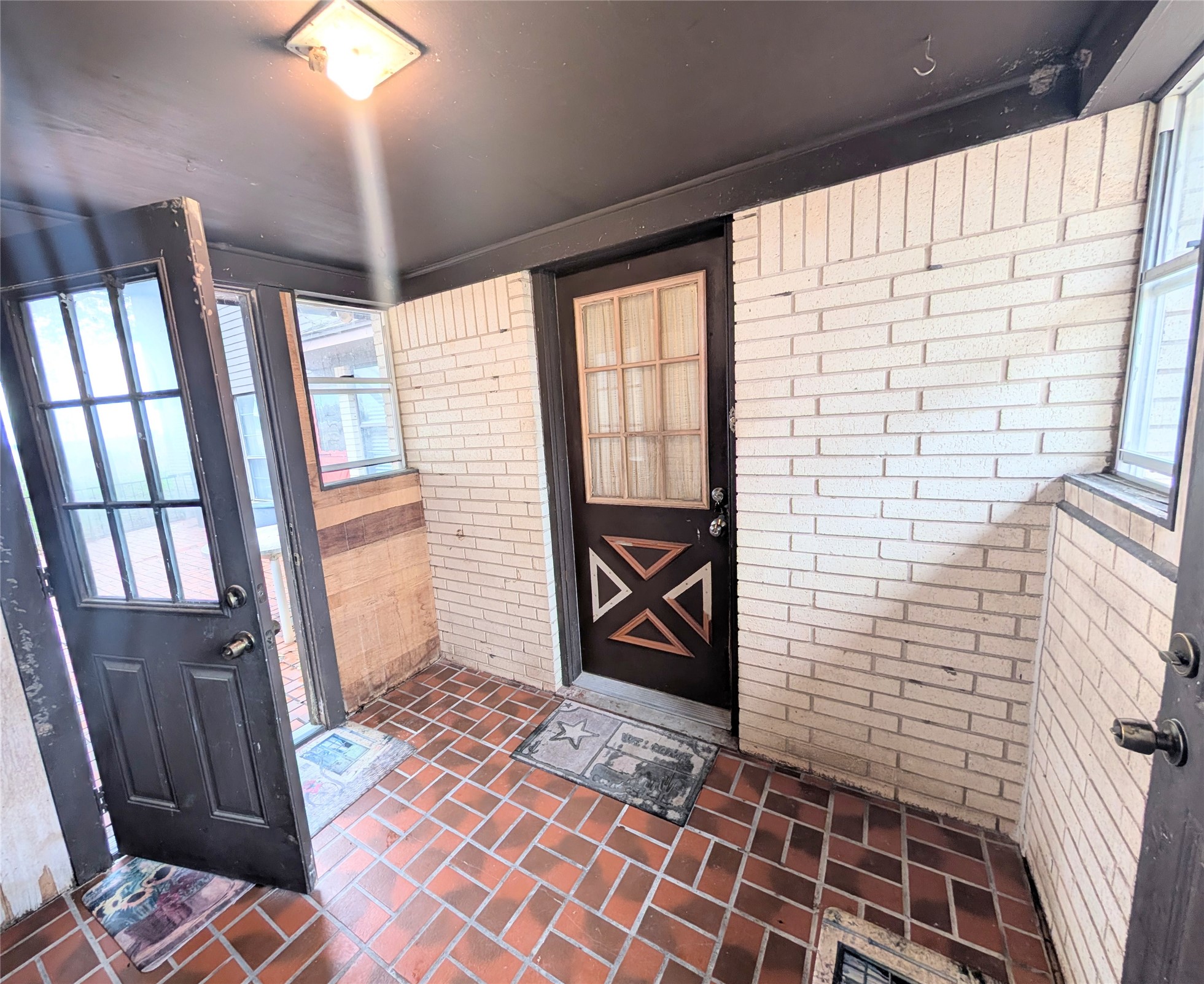4779 Mixville Road Sealy, TX 77474 - Photo 28 of 47 Small enclosed back porch area with doors from driveway side of house to kitchen, garage and backyard. Brick wall design, tiled floors and dark colored doors with glass panels provide natural light through adjacent windows.