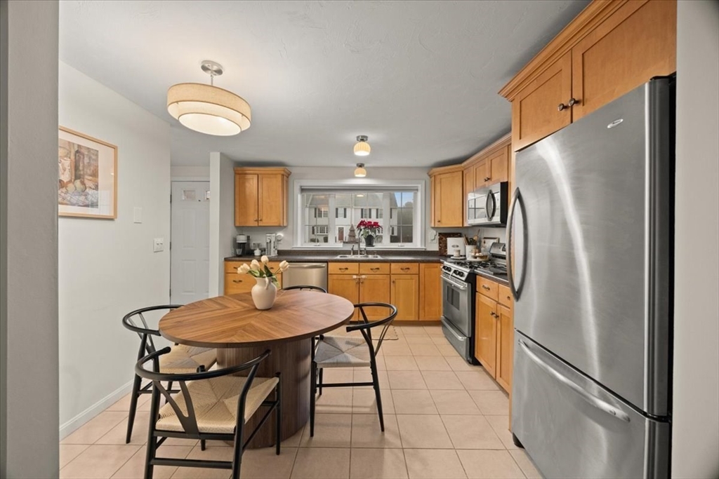 2697 Cranberry Highway, Unit 28 Wareham, MA 02571 - Photo 12 of 37 a kitchen with stainless steel appliances a refrigerator a stove a dining table and chairs with wooden floor