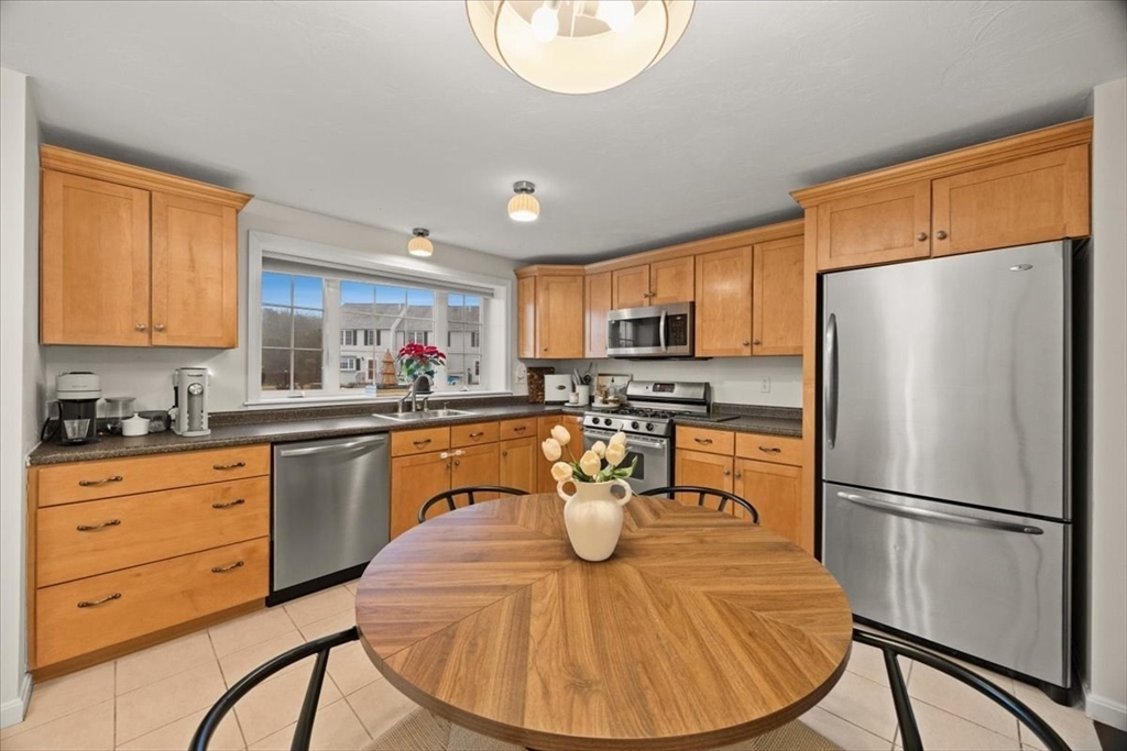2697 Cranberry Highway, Unit 28 Wareham, MA 02571 - Photo 10 of 37 a kitchen with stainless steel appliances granite countertop a refrigerator a stove a sink a dining table and chairs with wooden floor