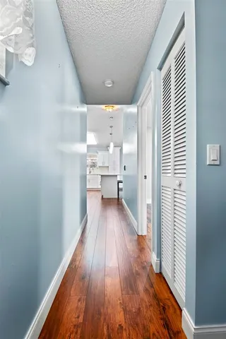 a view of a hallway with wooden floor and a bathroom