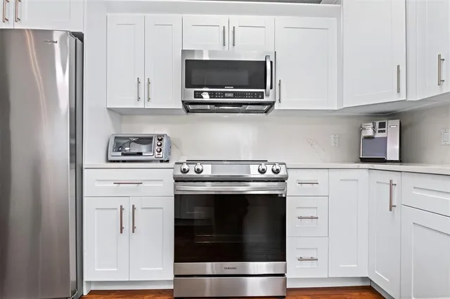 a kitchen with stainless steel appliances granite countertop a refrigerator stove and white cabinets