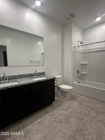 a bathroom with a granite countertop toilet sink and mirror