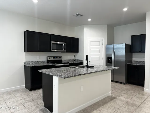 a kitchen with stainless steel appliances granite countertop a refrigerator and a sink