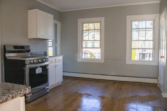 a kitchen with granite countertop wooden floors and white stainless steel appliances