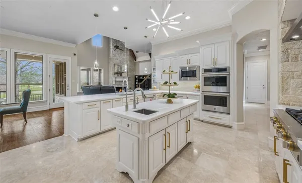 a large white kitchen with stainless steel appliances granite countertop a stove and a sink