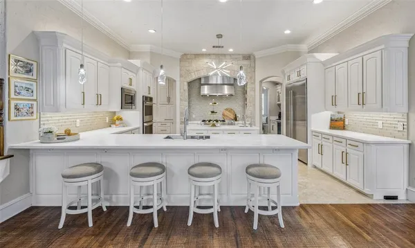 a kitchen with stainless steel appliances granite countertop a dining table chairs and white cabinets