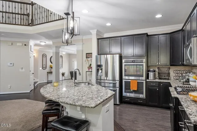 a kitchen with stainless steel appliances kitchen island granite countertop a refrigerator a stove and a sink with wooden floor