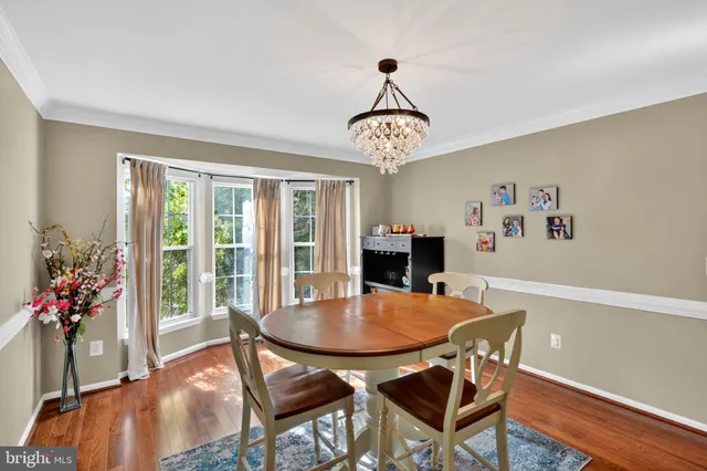 a dining room with wooden floor and chandelier