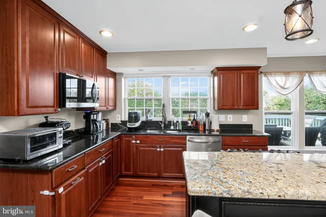 a kitchen with stainless steel appliances granite countertop wooden cabinets a stove top oven a sink and dishwasher next to a window