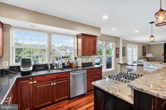 a kitchen with kitchen island granite countertop a sink stove and wooden cabinets