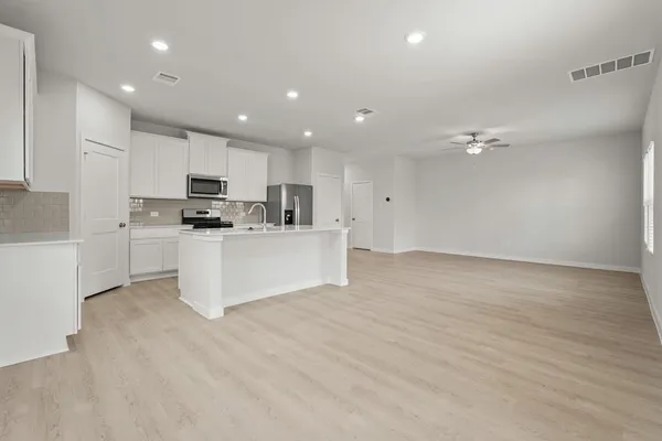 a large white kitchen with kitchen island a sink a stove a oven with white cabinets