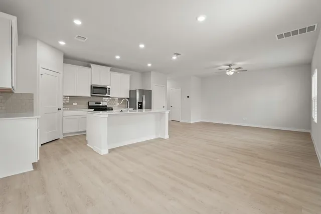 a large white kitchen with kitchen island a sink a stove a oven with white cabinets