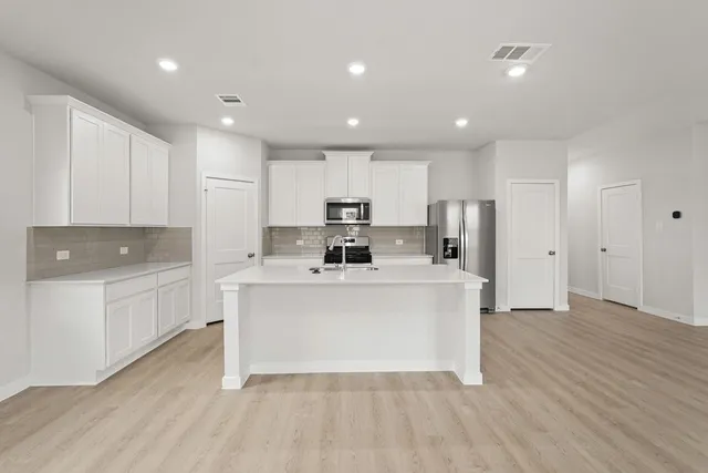 a view of kitchen with stainless steel appliances refrigerator stove microwave and cabinets