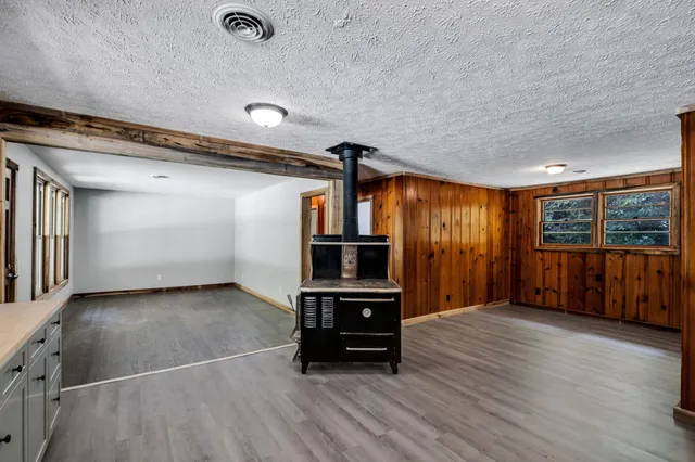 an empty room with wooden floor cabinet and windows