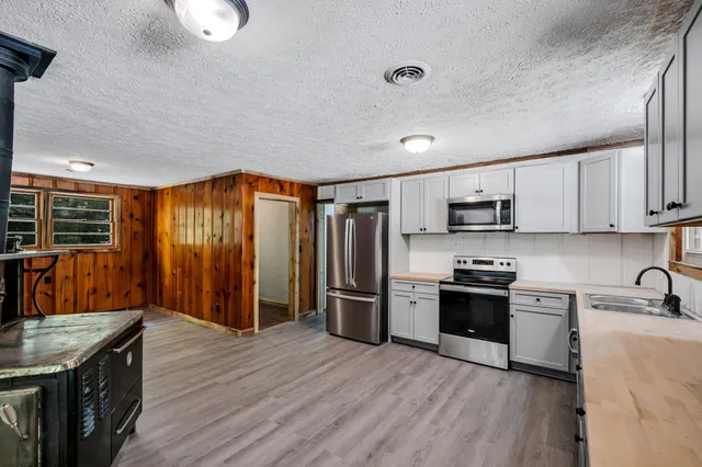 a kitchen with stainless steel appliances granite countertop a refrigerator a stove top oven a sink dishwasher and wooden cabinets with wooden floor