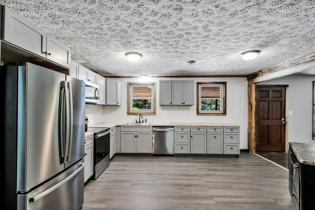 a large kitchen with stainless steel appliances granite countertop a refrigerator a stove a sink dishwasher and a refrigerator