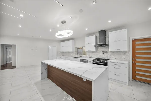 a view of an empty room with wooden floor and kitchen