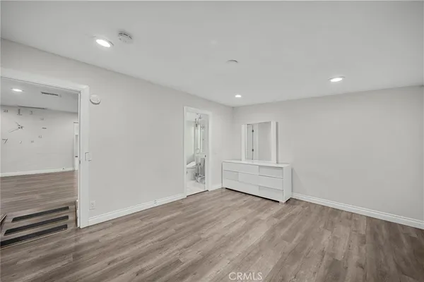 a view of an empty room with wooden floor and closet