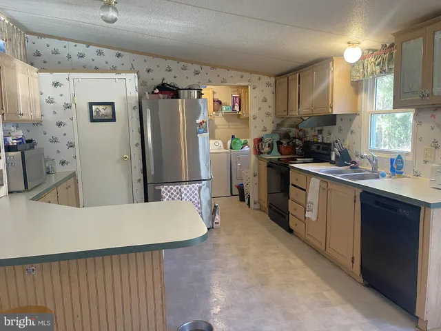 a kitchen with stainless steel appliances a refrigerator a sink dishwasher a stove and white cabinets